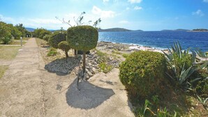 Ein Küstenweg mit ordentlich geschnittenen Büschen und freiem Blick auf das Meer.
