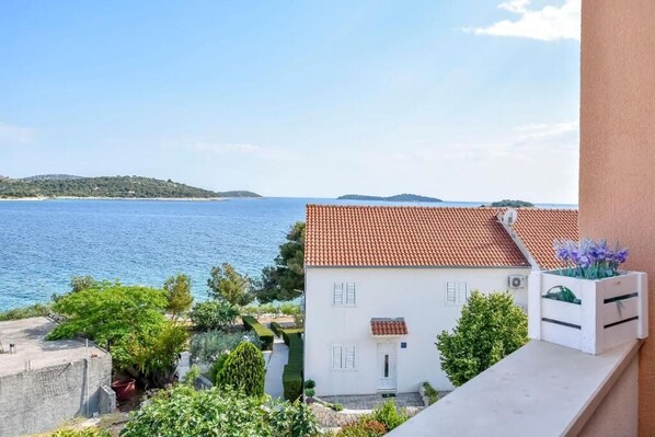 Un bâtiment blanc, surmonté d’un toit recouvert de tuiles rouges, qui surplombe une étendue d’eau et une île lointaine.