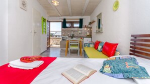 A compact room with a bed, a desk, and a kitchenette. - Apartment Mezaroca (Razanj)