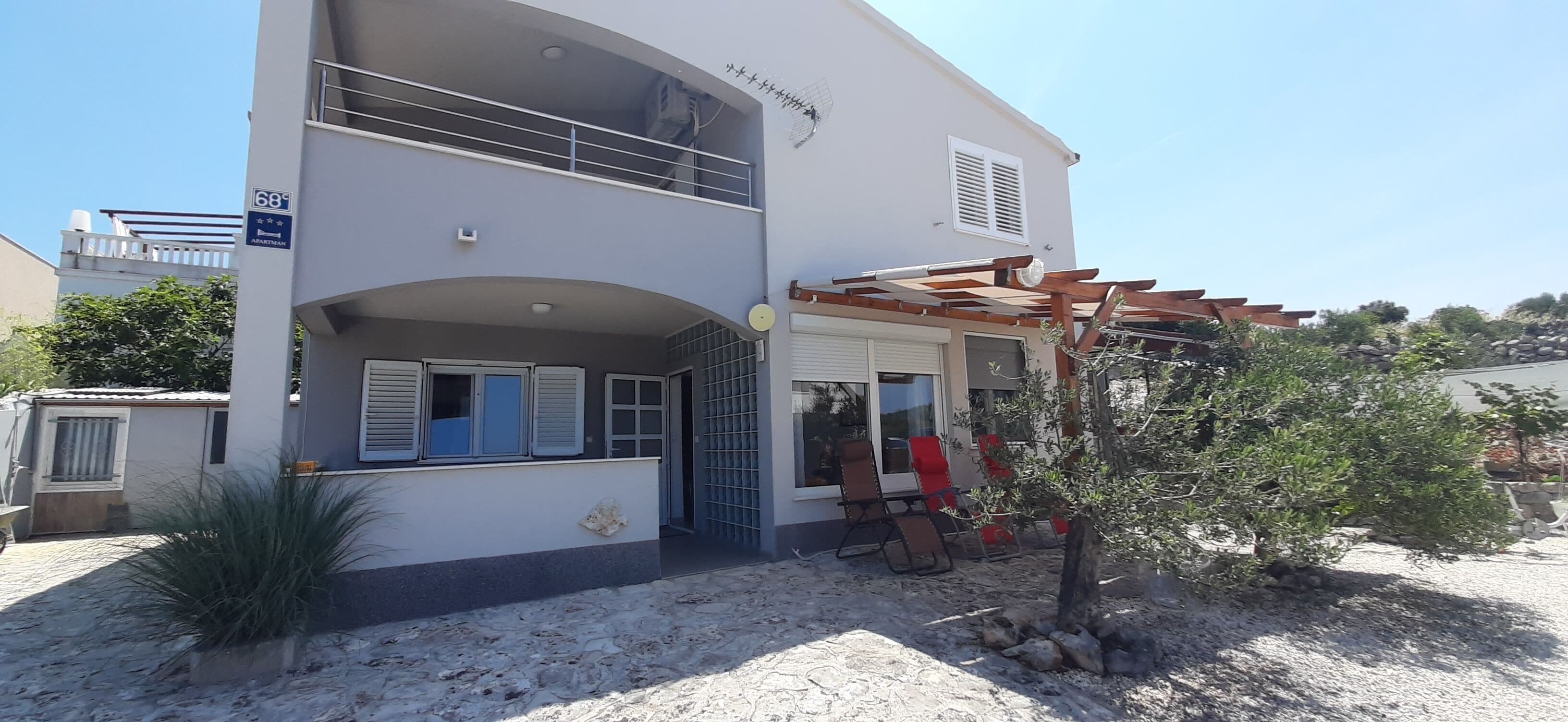 Un edificio a due piani con un balcone, una pergola e posti a sedere all'aperto.