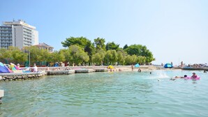 A public swimming area with a stone pier, people swimming, and a building labeled 'PUNTA' in the background. - Apartments Grgo (Vodice)