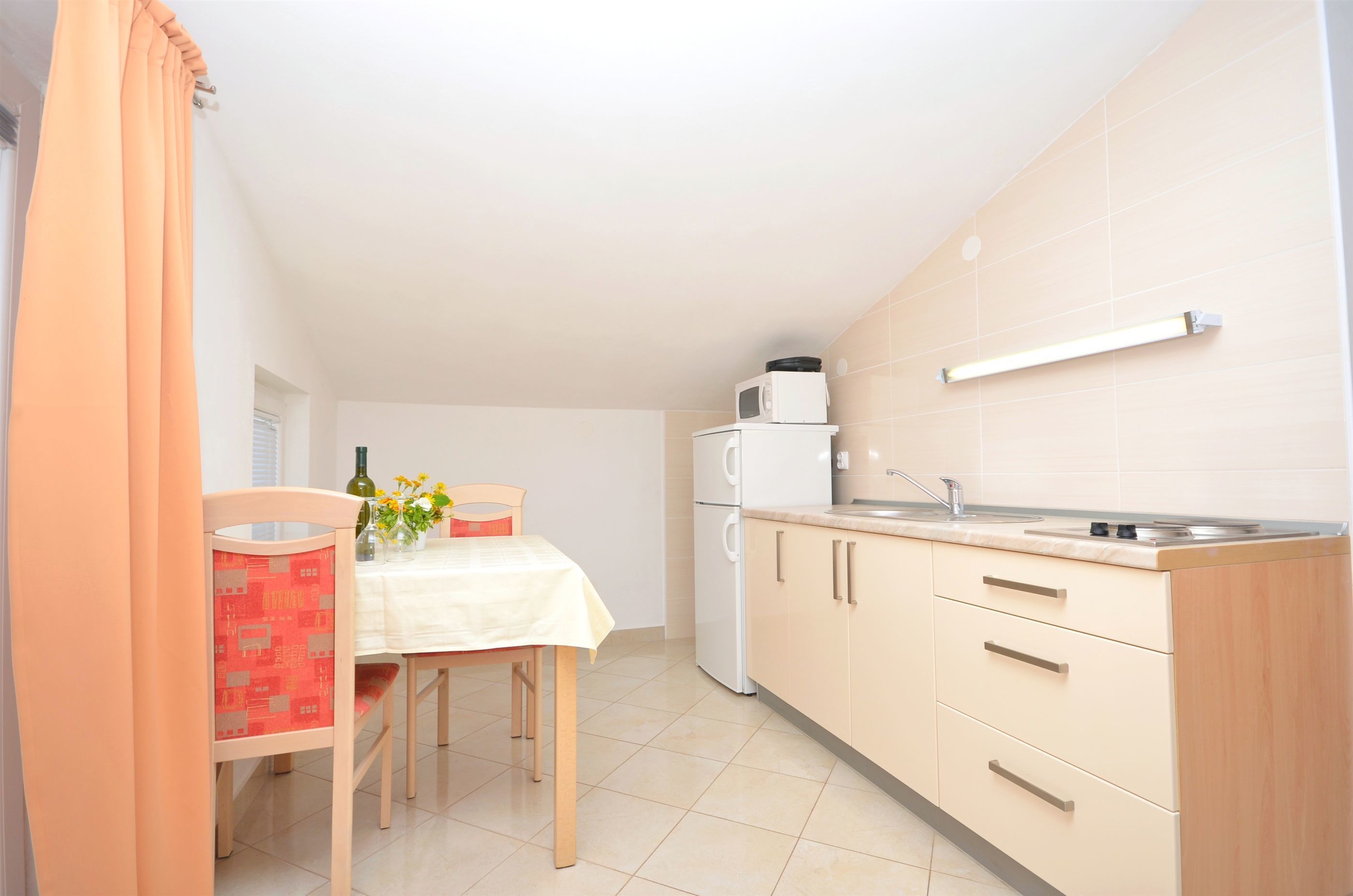 A small kitchen with a dining table, chairs, a microwave, and a sink.