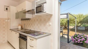 Una cucina moderna con forno a incasso, microonde e un'ampia finestra vista giardino.