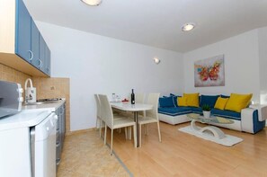 A modern kitchen with a dining area, a sofa set, and a painting on the wall.