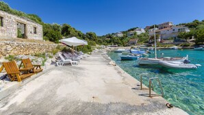 A coastal marina with clear water, wooden chairs, and a stone wall. - Apartments Otjana (Sevid)