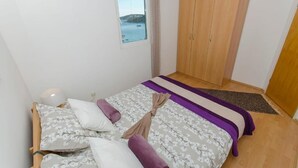 A bedroom with a bed, a window with a view of the sea, a wardrobe, and a small table. - Apartments Otjana (Sevid)