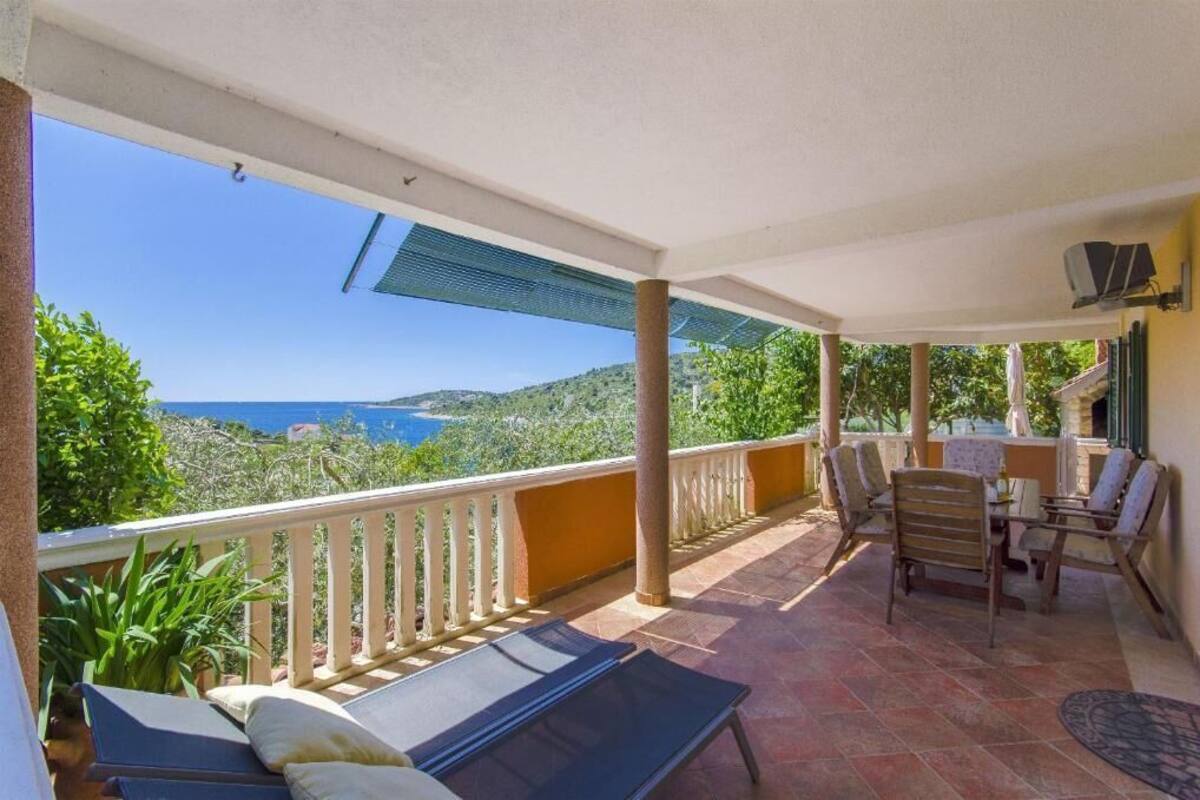 A covered outdoor area with a table and chairs, a sun lounger, and a view of the sea.