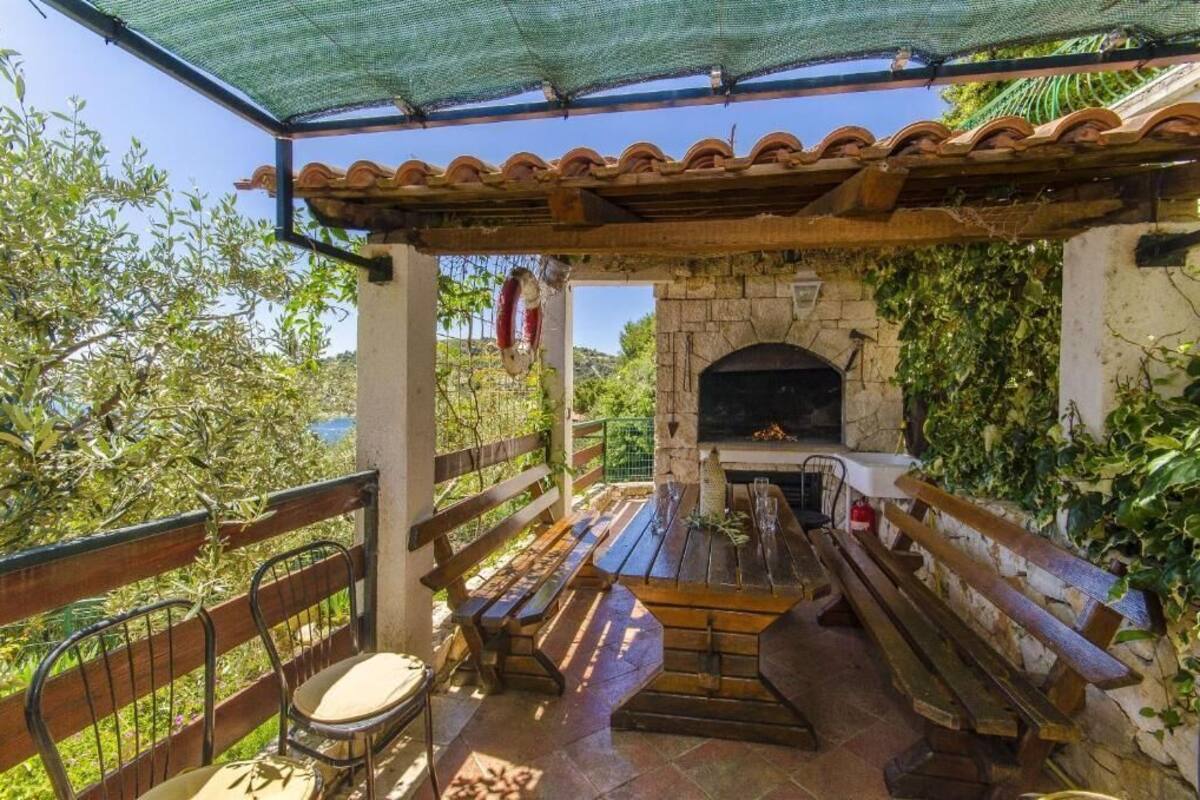 An outdoor patio with a stone fireplace, wooden benches, and a pergola.