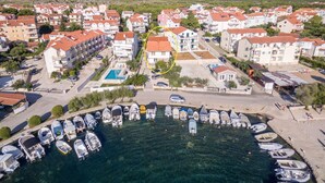 Une zone résidentielle côtière comprenant de nombreux immeubles d’appartements, une marina avec plusieurs bateaux, et un ciel bleu dégagé.