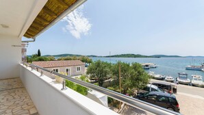 Un balcon offrant une vue sur un port de plaisance, des bateaux et des collines lointaines.