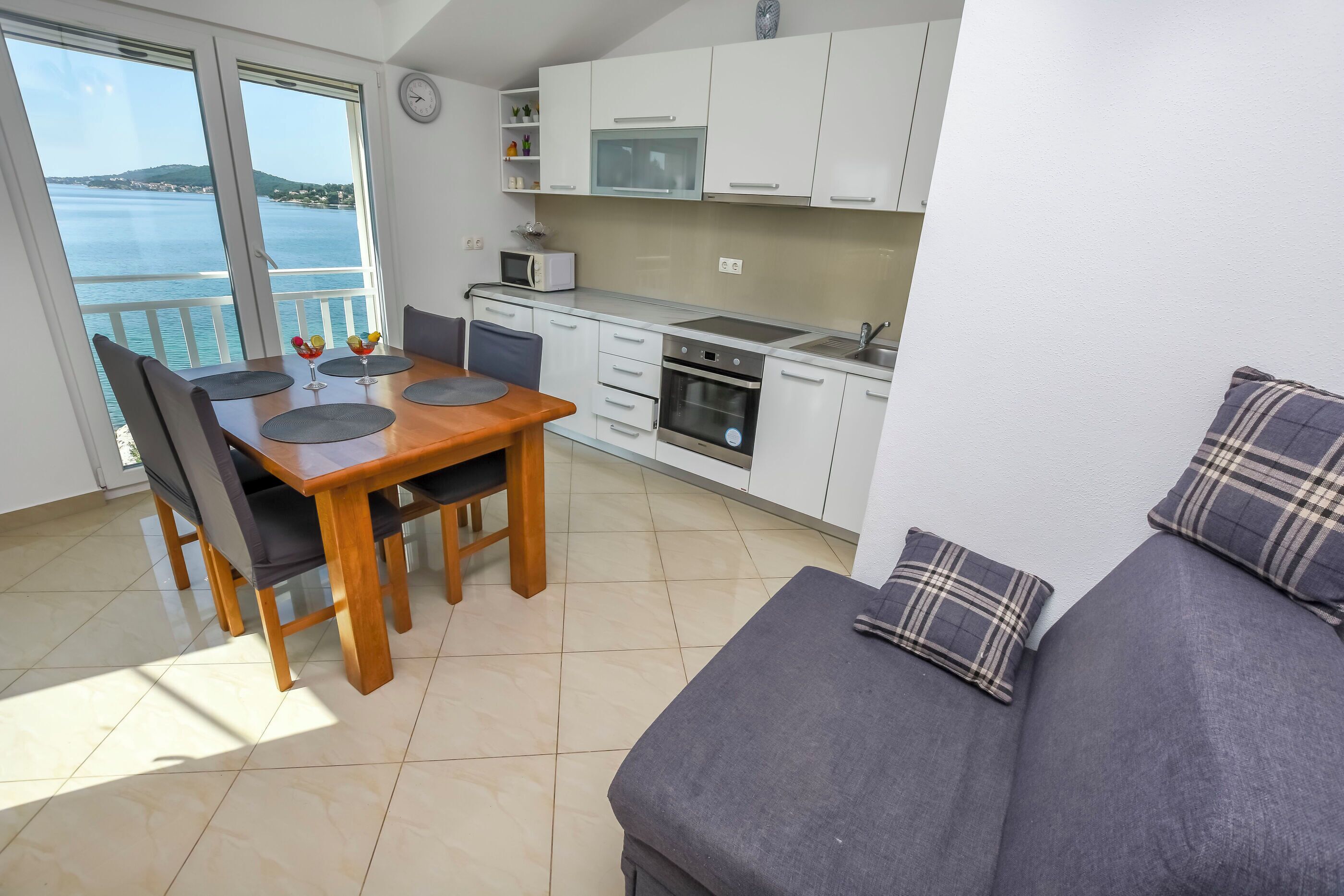 A modern kitchen with white cabinets, a microwave, oven, and a dining area with a wooden table and chairs.