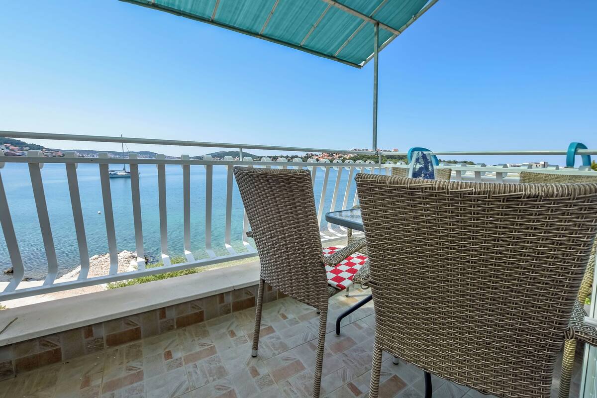 Un balcon doté de meubles en osier et offrant une vue sur la mer.