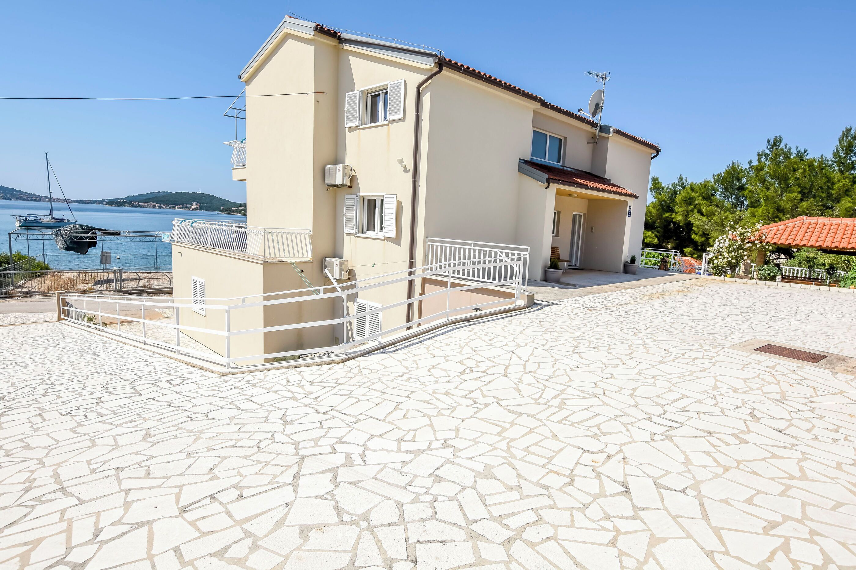 A two-story building with a tiled patio, a balcony, and a view of the sea.
