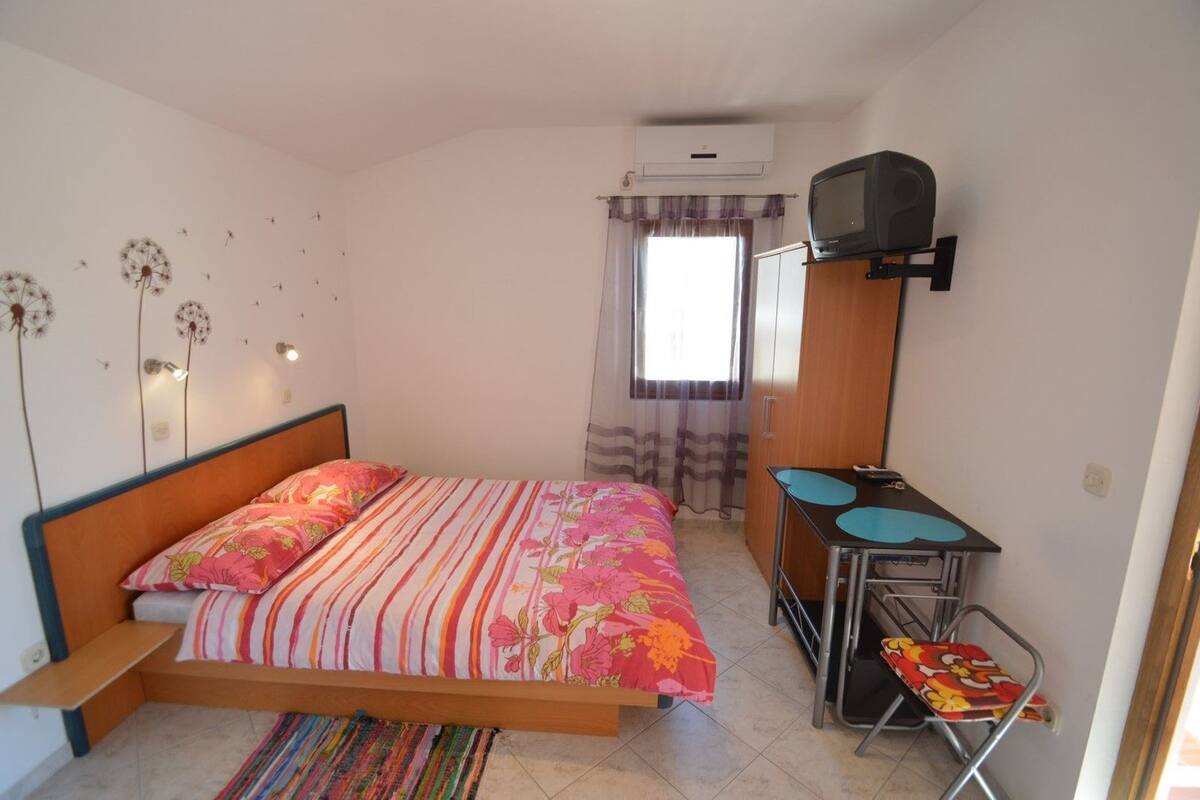 Une chambre à coucher comprenant un lit, un bureau, une chaise et un appareil de climatisation.