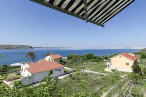 A coastal residential area with houses, a clear blue sky, and a view of the sea.