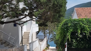 A coastal road leading to a white building with a stone staircase and a view of the sea. - House Fani (Zastrazisce)