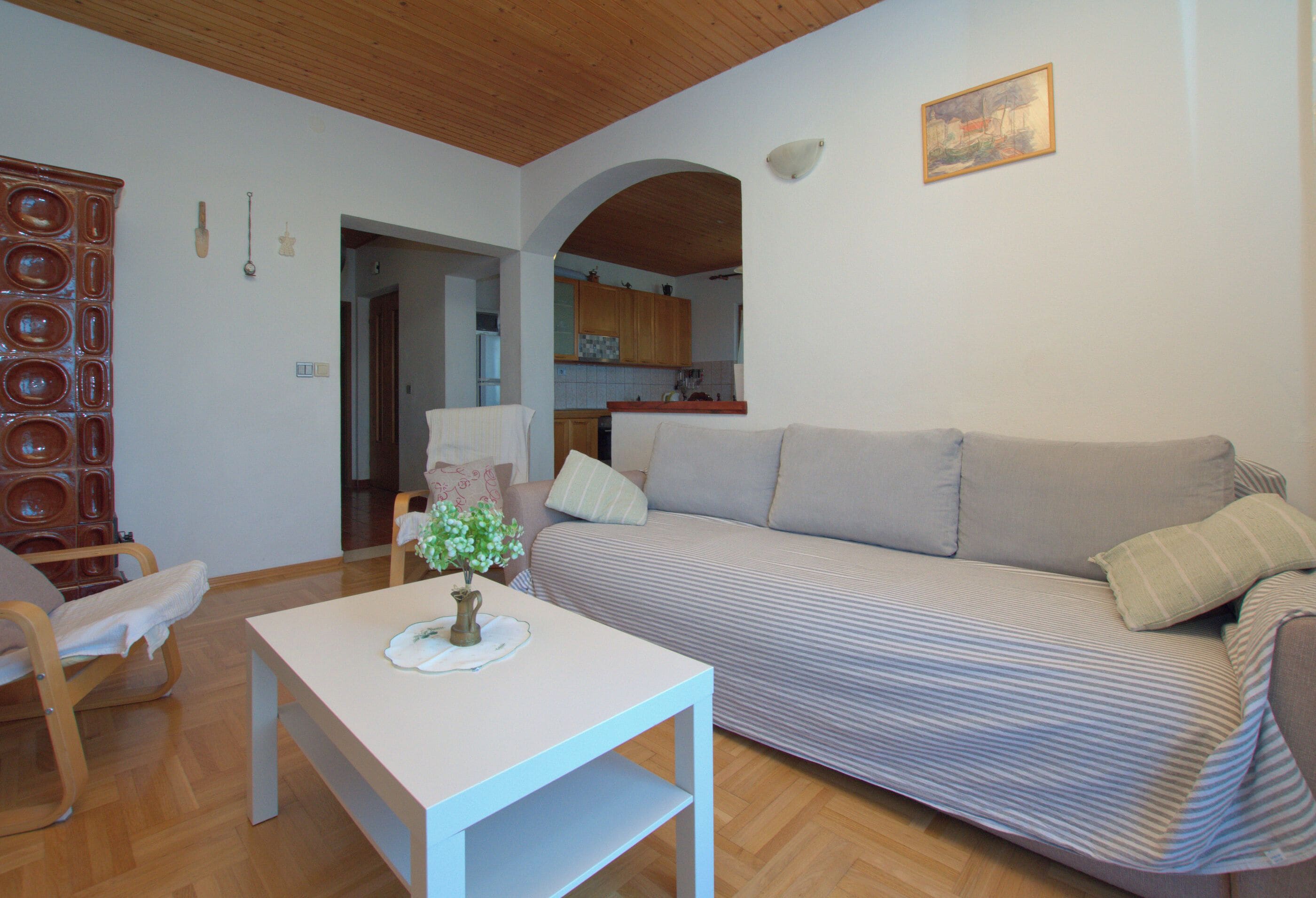 Una sala de estar con sofá, una mesa y una cocina al fondo.