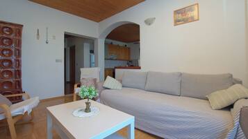 Una sala de estar con sofá, una mesa y una cocina al fondo.