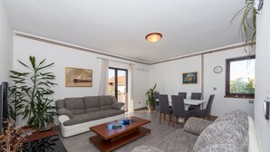 Un salon moderne avec un canapé gris, une table basse et un coin repas comprenant des chaises et une table.