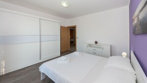 Une chambre moderne avec un grand lit, une armoire, un bureau et une porte donnant sur une salle de bain.