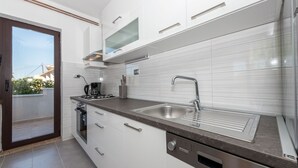 Une cuisine moderne avec des meubles blancs, un évier en acier inoxydable et un lave-vaisselle.