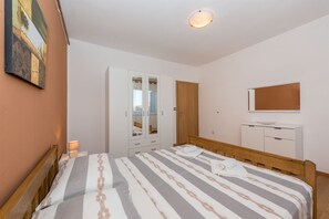 A bedroom with a bed, wardrobe, bedside table, and a mirror on the wall. - Apartments Snjezana (Tisno)