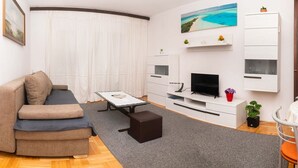 Una sala de estar moderna con un sofá, una mesa de centro, un televisor y una pequeña mesita auxiliar.