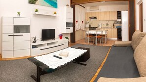 Una sala moderna con televisor de pantalla plana, un sofá y una mesa de centro con camino de mesa de encaje.