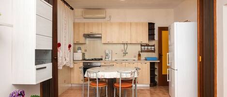 A compact kitchen with a dining table and chairs, a refrigerator, and a microwave.