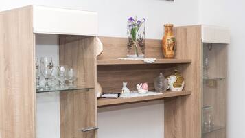A wooden cabinet with shelves containing glassware, a vase with flowers, and decorative items.