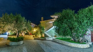 Une cour pavée agrémentée de jardinières en pierre, un escalier et un bâtiment doté d’un luminaire.