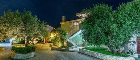 A paved courtyard with stone planters, a staircase, and a building with a light fixture.