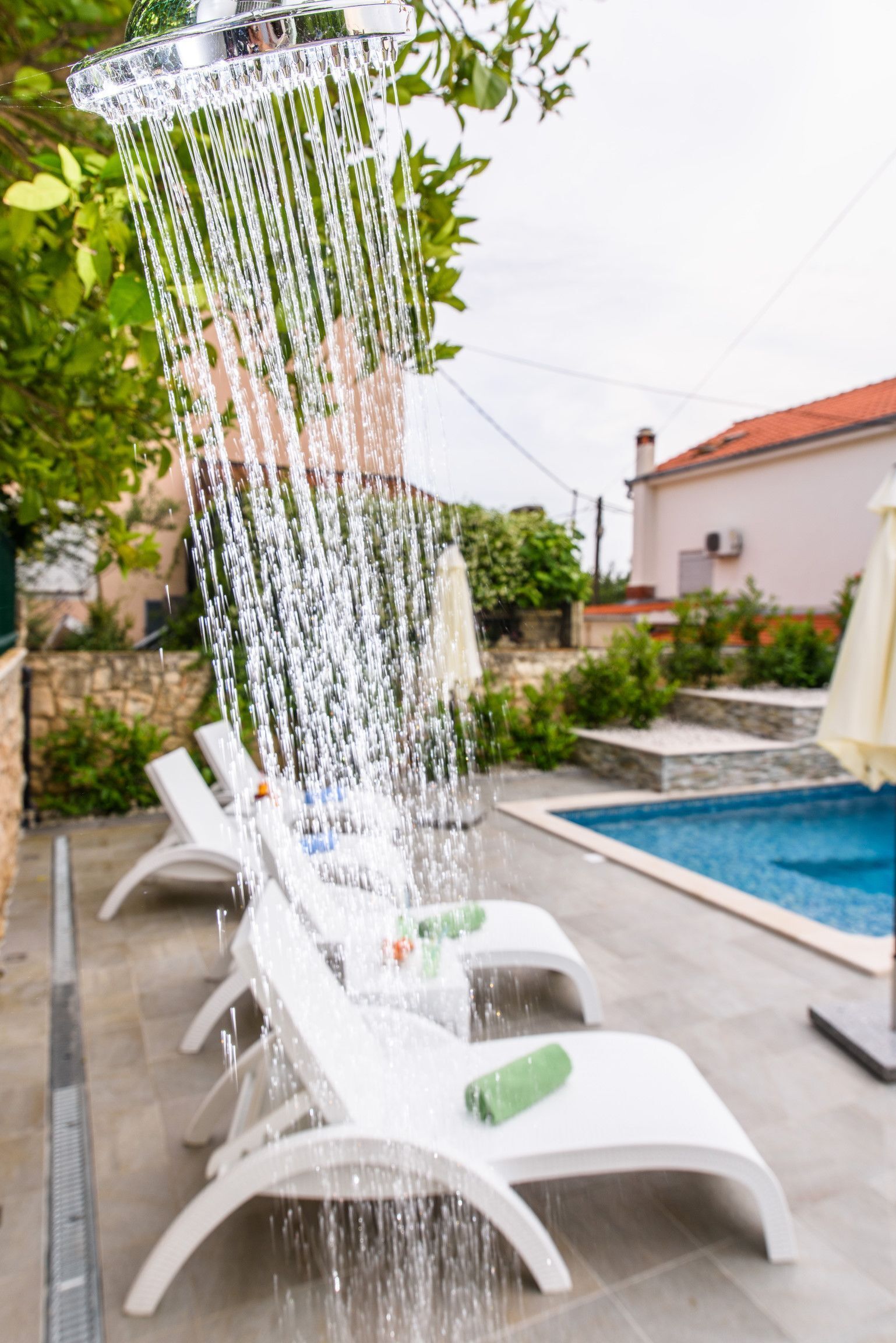 A water feature with multiple jets, surrounded by lounge chairs and a pool.