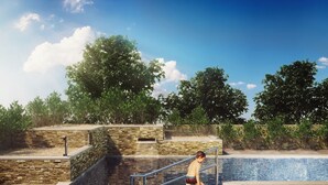 Une piscine aux murs en pierre et un enfant qui joue dans l’eau.