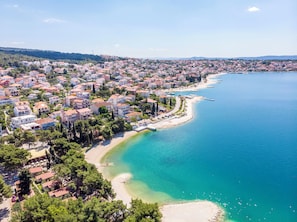 Vue aérienne d’une ville côtière avec des immeubles résidentiels, une plage et une mer bleue et limpide.