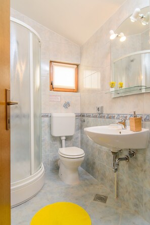 Un baño con ducha, inodoro, lavabo y ventana.
