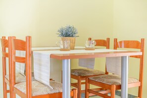 Una mesa de comedor con un centro de mesa vegetal tejido, rodeada de sillas de madera con asientos acolchados.