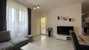 Una sala de estar moderna con sofá, televisor y comedor.