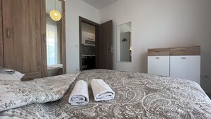 Un dormitorio con una cama grande, dos toallas enrolladas, un armario, un espejo y una lámpara colgante.