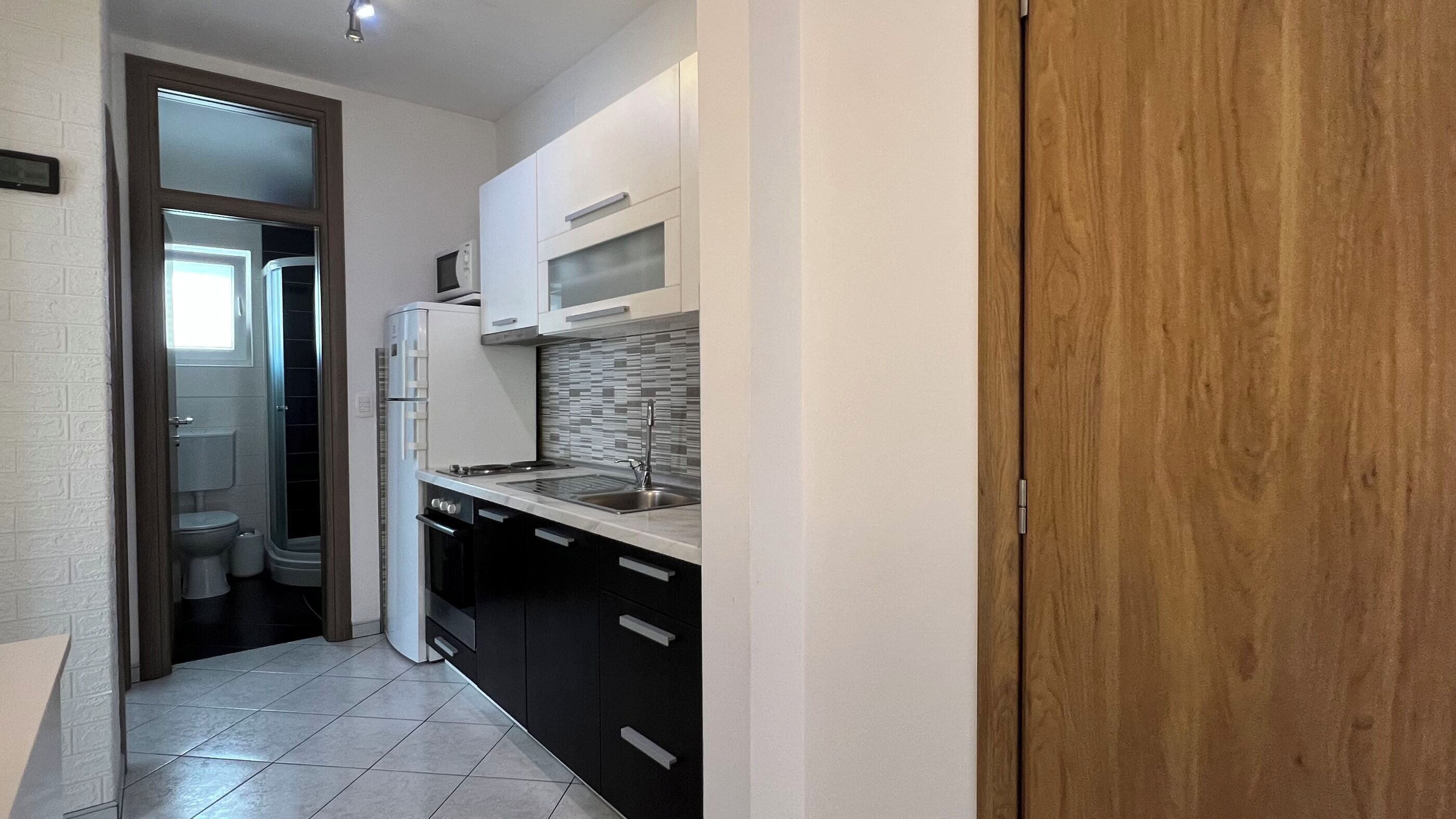 Appartement (A1) | Privékeuken | Een koelkast, een kookplaat, kookgerei, borden en bestek