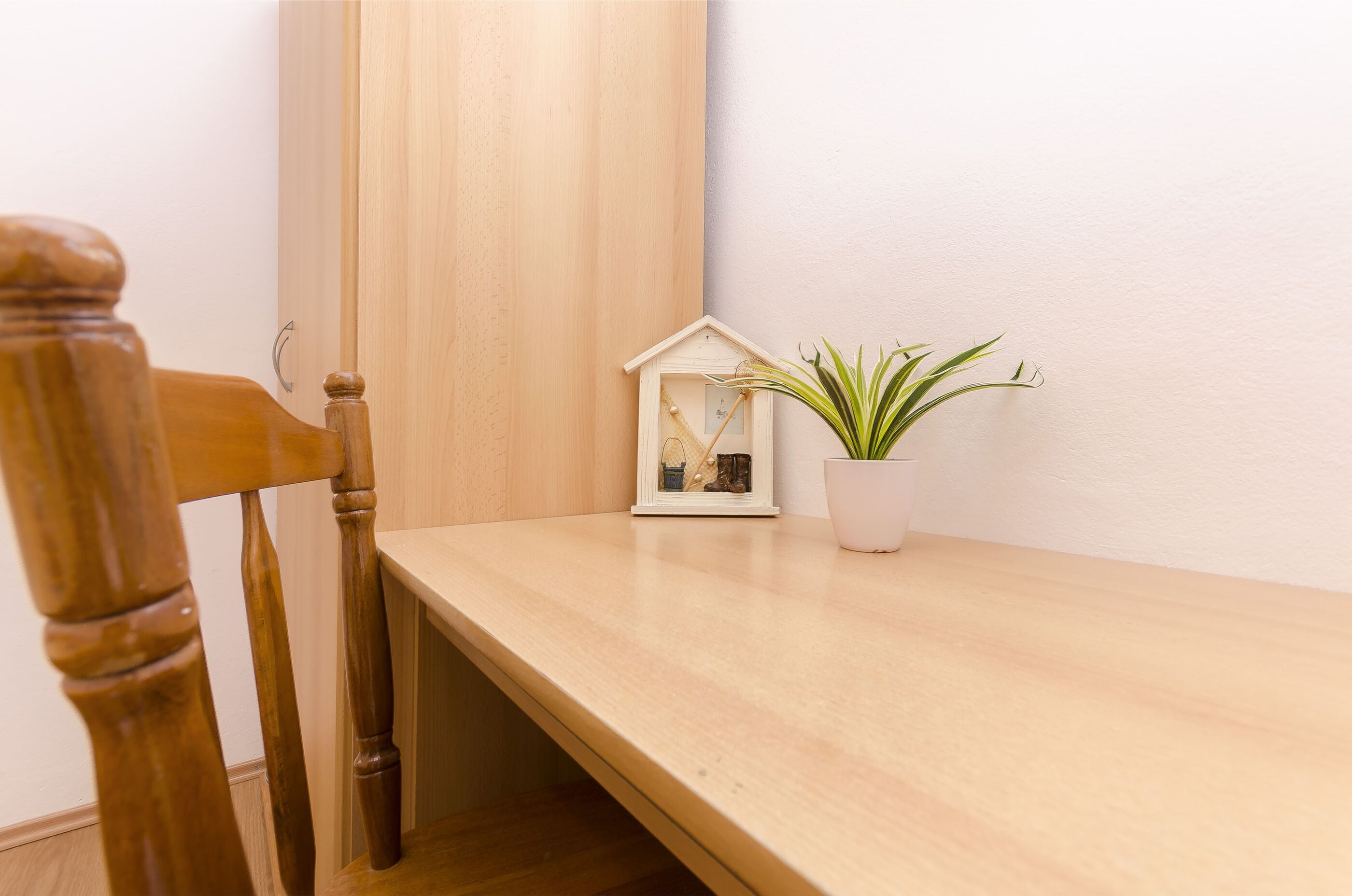 A wooden table with a small house-shaped photo frame and a potted plant.
