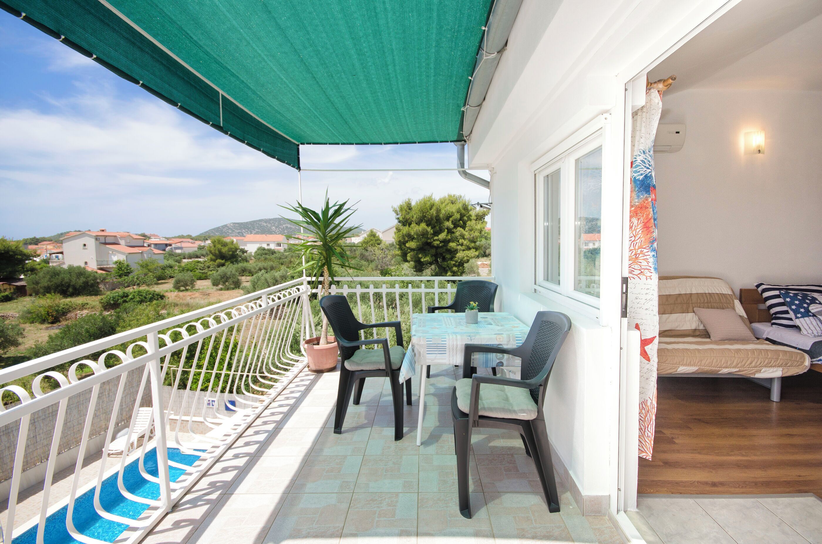 A balcony with a table and chairs, a small pool, and a view of the surrounding area.