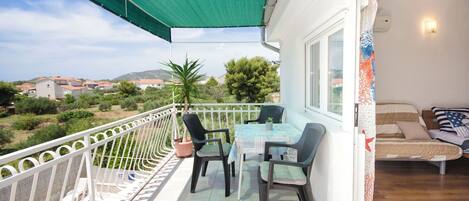A balcony with a table and chairs, a small pool, and a view of the surrounding area.