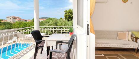 A balcony with a pool, a sofa, and a table with chairs.