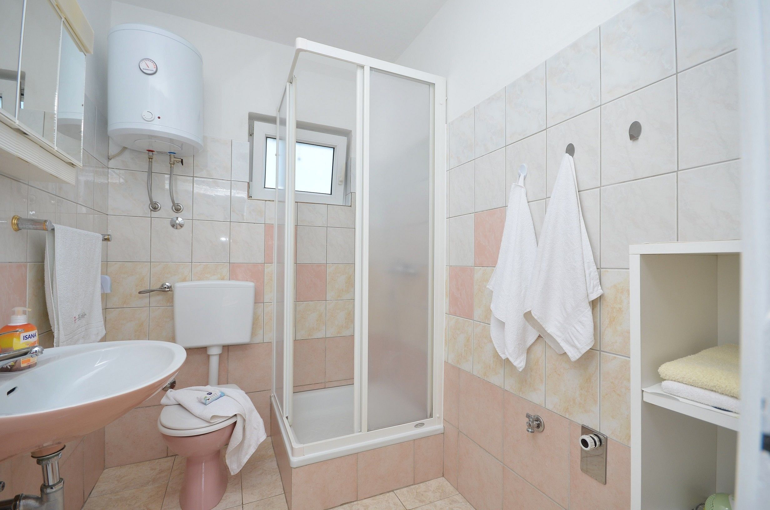 A bathroom with a toilet, sink, shower, and towel rack.