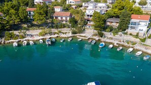A coastal area with boats docked along a stone quay, surrounded by residential buildings with red-tiled roofs. - Apartment Tina (Starigrad - Paklenica)