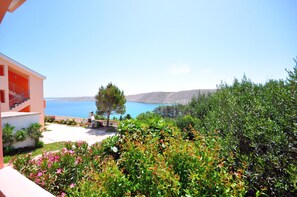 A modern building with a balcony overlooking a clear blue sea and hills. - Apartments Andelo (Vlasici)