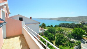 A balcony with a view of a coastal landscape, including a body of water and distant hills. - Apartments Andelo (Vlasici)