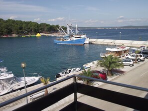 A marina with boats docked, a pier, and a view of the sea and distant hills. - Apartments Milo (Kukljica)