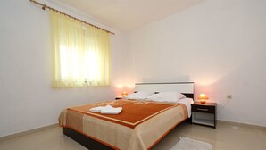 Ein Schlafzimmer mit Bett, Nachttischen, einer Lampe, einem Fenster mit Vorhängen und einem Teppich.